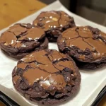 Four rich and fudgy brownie mix cookies with crackly tops and melted chocolate drizzle, arranged neatly in a bakery-style box.