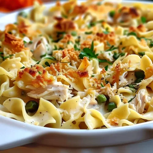 Homemade baked chicken noodle casserole with egg noodles, shredded chicken, and peas