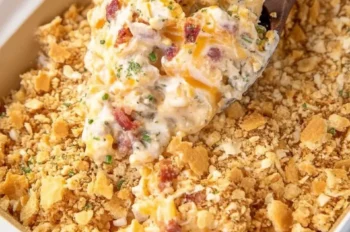 Overhead view of Crack Chicken Casserole being scooped out of a casserole dish showing creamy texture, bacon, and golden cracker topping