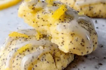 Soft lemon poppy seed cookies with lemon curd filling, drizzled with lemon glaze and sprinkled with poppy seeds, displayed on parchment paper.