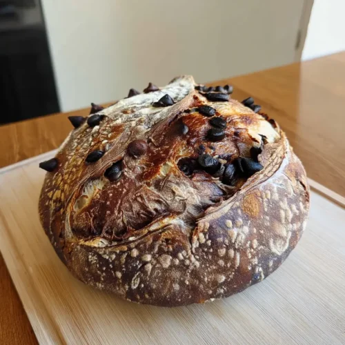 Freshly baked chocolate marbled sourdough bread with chocolate chips on a wooden cutting board