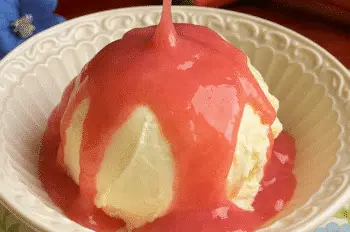 Rhubarb sauce being poured over vanilla ice cream in a floral bowl