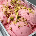 Freshly churned rosewater pistachio gelato in a metal container, garnished with chopped pistachios