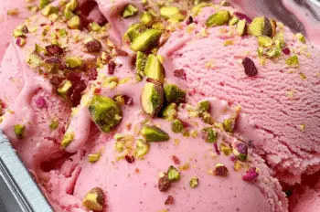Freshly churned rosewater pistachio gelato in a metal container, garnished with chopped pistachios