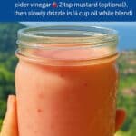 Hand holding a mason jar of pink rhubarb vinaigrette in front of a scenic landscape, overlaid with text instructions for making the vinaigrette.